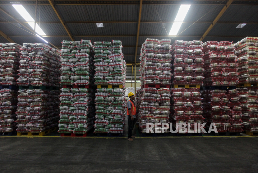 Petugas berjalan di dekat tumpukan beras premium yang siap untuk diedarkan di Gudang RPC PT Food Station, Cipinang, Jakarta, Rabu (21/2/2024). 