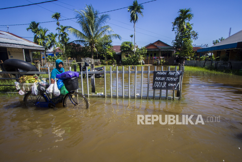 Seorang warga menuntun sepedanya menorobos banjir yang menggenangi jalan akibat rob (ilustrasi)