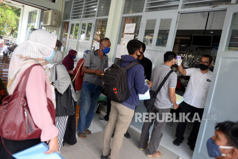 Petugas memeriksa suhu tubuh warga yang akan melakukan perekaman KTP elektronik di Kantor Dinas Kependudukan dan Pencatatan Sipil (Disdukcapil) Kabupaten Sleman, Yogyakarta.