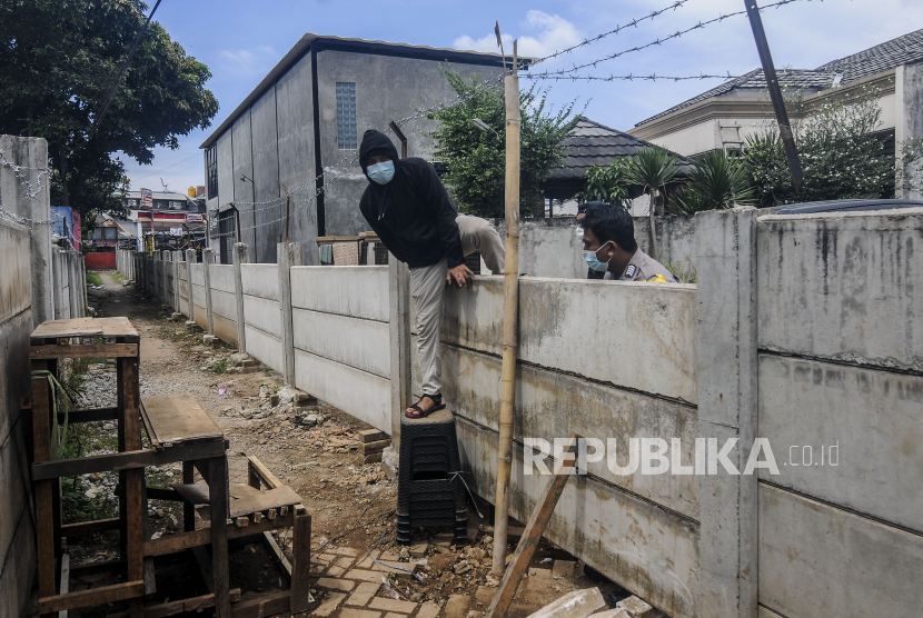 Warga memanjat tembok untuk memasuki rumahnya di Ciledug, Kota Tangerang, Banten. Tembok beton sepanjang 300 meter dengan tinggi 2 meter serta dipasang kawat duri itu menutup akses menuju rumah dan tempat usaha milik warga sejak 21 Februari 2021 karena permasalahan sengketa lahan.