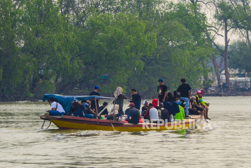 Pengunjung menaiki perahu untuk menuju lokasi konservasi lutung jawa dan wisata mangrove di Muaragembong, Kabupaten Bekasi, Jawa Barat. Bekas kantor Kecamatan Muaragembong diubah menjadi fasilitas wisata.
