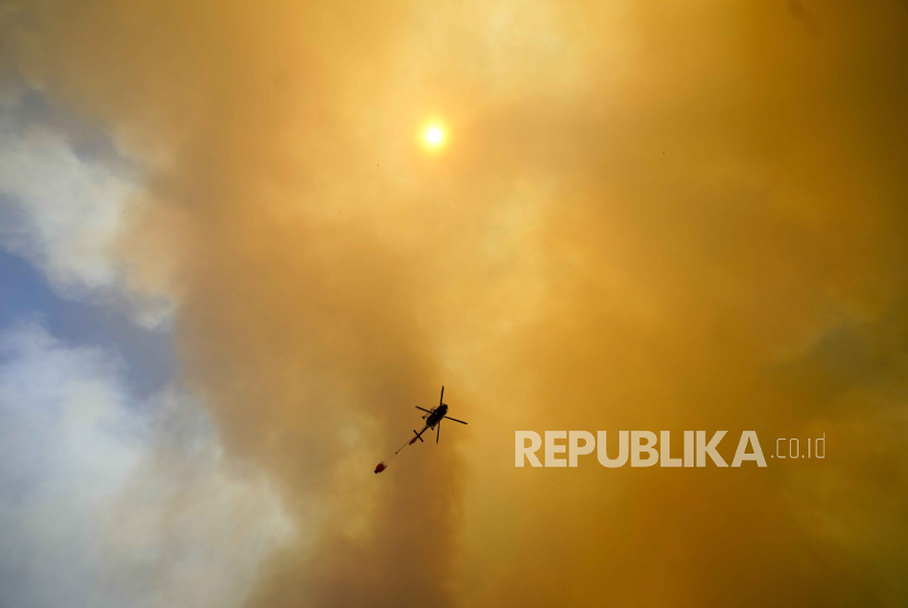Gumpalan asap membubung ke langit saat helikopter terbang di atas kebakaran hutan yang meluas di Chili.