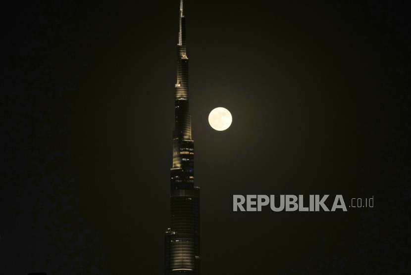 Bulan purnama super terbit di belakang  menara tertinggi dunia Burj Khalifa di Dubai, Uni Emirat Arab, Senin, (3/7/2023).