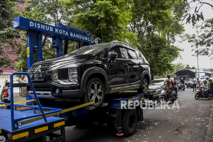Petugas Dinas Perhubungan (Dishub) Kota Bandung menderek mobil yang parkir sembarangan menggunakan mobil derek hidrolik otomatis.