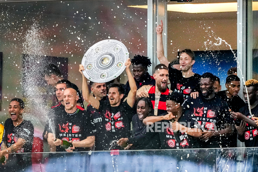 Pemain Bayer Leverkusen merayakan kemenangan setelah menjadi juara Bundesliga di Leverkusen, Jerman, Ahad (14/4/2024). Bayer Leverkusen memastikan gelar juara Bundesliga 2023/2024 usai mengalahkan Werder Bremen dengan skor telak 5-0. Kemenangan ini sontak dirayakan puluhan ribu pendukung setianya yang memadati Stadion BayArena. Para pendukung tumpah ruah di tengah lapangan merayakan kesuksesan tim kesayangannya.
