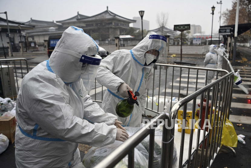 Dalam foto yang dirilis oleh Kantor Berita Xinhua, para pekerja yang mengenakan pakaian pelindung mendisinfeksi sayuran yang dikemas di area perumahan yang dikarantina di Xi