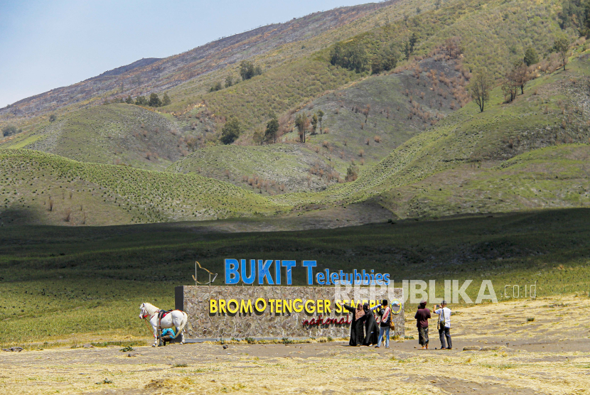 Pengunjung saling bercengkerama dengan latar savana Gunung Bromo di Bukit Teletubbies, Probolinggo, Jawa Timur.