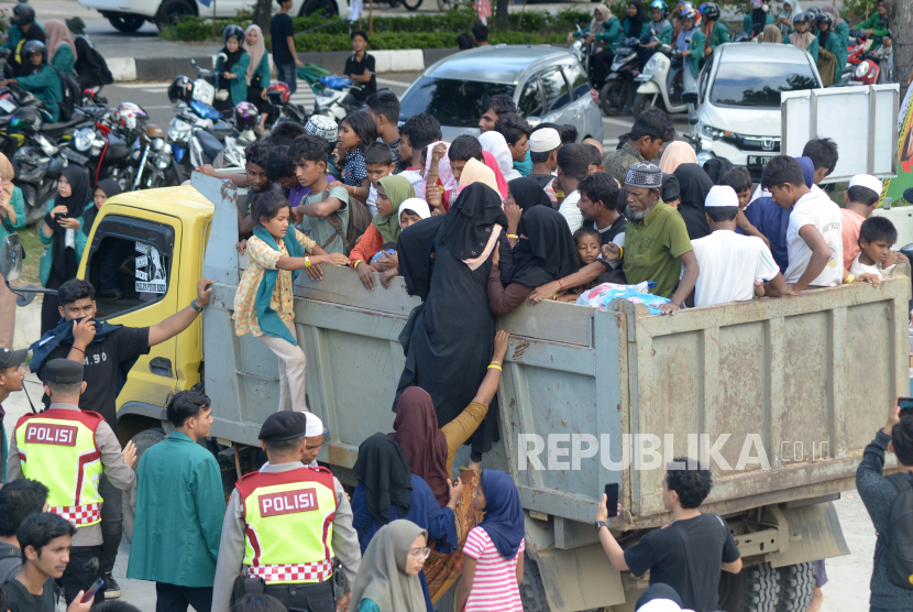 Mahasiswa dan polisi membantu menaikkan imigran etnis Rohingya ke truk saat pemindahan paksa di penampungan sementara gedung  Balai Meuseuraya Aceh (BMA), Banda Aceh, Aceh, Rabu (27/12/2023).