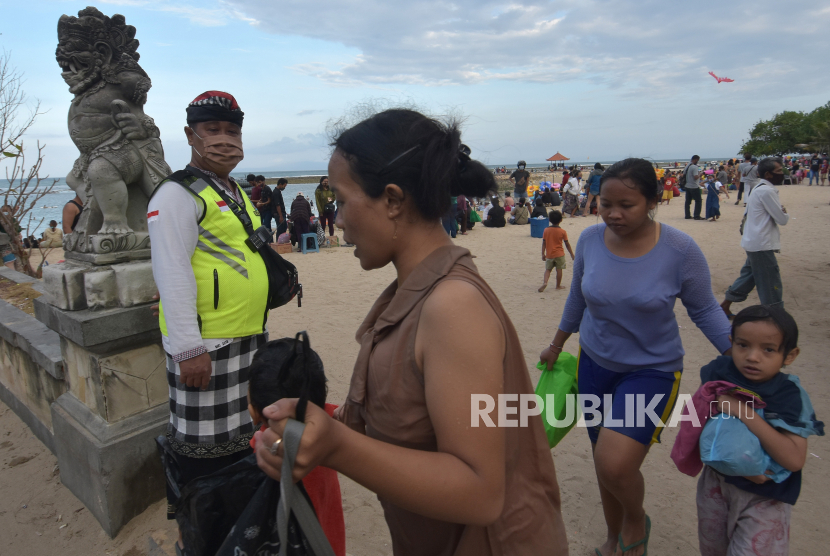 Pecalang atau petugas keamanan desa adat di Bali menegur warga yang melepas masker saat liburan Hari Raya Galungan di Pantai Sanur, Denpasar, Bali, Kamis (17/9/2020). Objek wisata tersebut masih dibuka meskipun sejumlah ruang publik di Denpasar ditutup menyusul terus melonjaknya kasus penularan COVID-19 di daerah itu. 