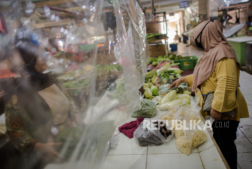 Warga membeli sayuran dibalik tirai plastik di Pasar Bandeng, Kota Tangerang, Banten, Selasa (2/6). Pengelola pasar Bandeng mewajibkan pedagang untuk memasang tirai plastik sebagai antisipasi penyeberan COVID-19