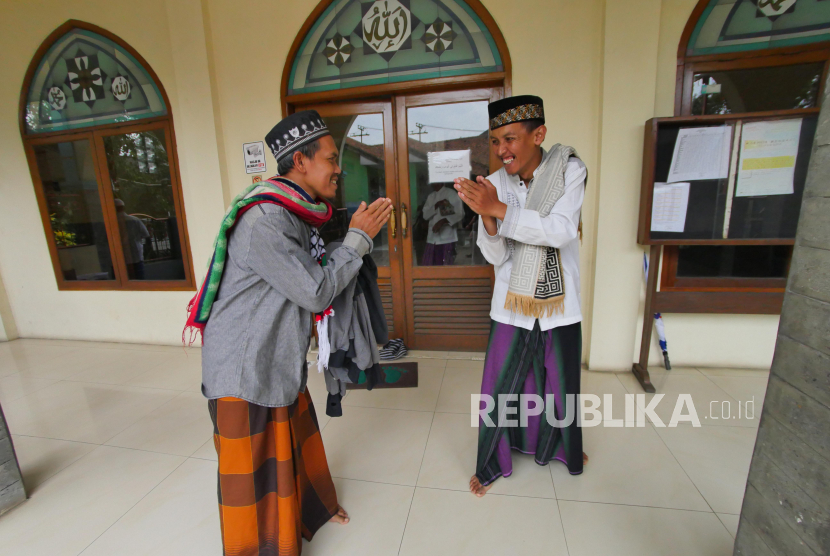 Dua jamaah Masjid Al Furqan bersalaman tanpa bersentuhan tangan usai pelaksanaaan shalat Jumat di Kompleks Jaka Purwa, Kecamatan  Bandung Kidul, Bandung, Jumat (20/3). Organisasi Kesehatan Dunia (WHO) secara resmi menganjurkan dan mendorong penggunaan frasa physical distancing yang berarti menjaga jarak fisik. WHO menyarankan penggunaan frasa ini alih-alih social distancing (menjaga jarak sosial).