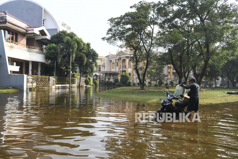 Pengendara motor menata barang bawaannya di atas motor yang mogok akibat banjir rob (ilustrasi)