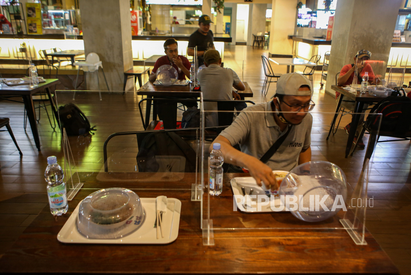 Pengunjung makan siang di salah satu gerai makanan yang menggunakan sekat jarak di Tangcity Mall, Kota Tangerang, Banten, Senin (22/6/2020). Pusat perbelanjaan di Kota Tangerang mulai kembali dibuka pada Penerapan Sosial Berskala Besar (PSBB) dengan menerapkan protokol kesehatan. 