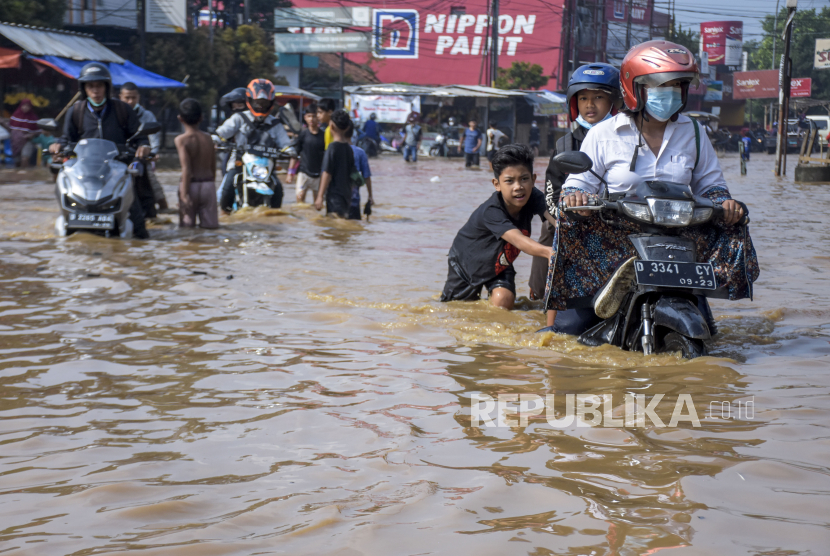 Sejumlah warga mendorong kendaraannya yang mogok saat banjir menggenangi Jalan Raya Dayeuhkolot, Kecamatan Dayeuhkolot, Kabupaten Bandung. Hujan dan luapan Sungai Citarum sebabkan banjir di tiga kecamatan Kabupaten Bandung.