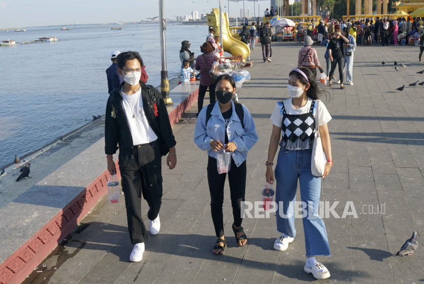 Orang-orang yang memakai masker berjalan di dekat Istana Kerajaan di Phnom Penh, Kamboja, (29/12/2023).