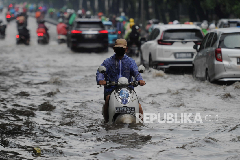 Pengendara motor melewati genangan air di Jalan Raya Tanjung Barat, Jakarta.