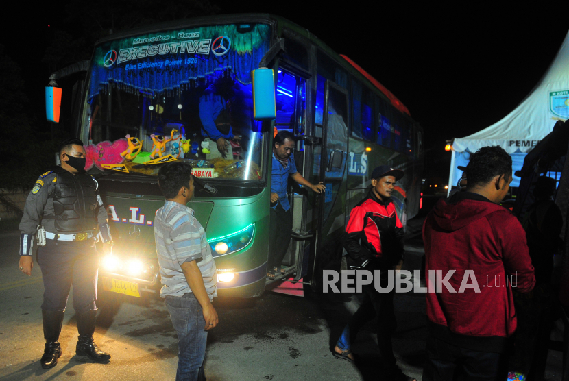 Petugas mengarahkan penumpang bus antar kota antar provinsi (AKAP) untuk pemeriksaan suhu tubuh saat memasuki Kota Jambi di Jambi, Senin (13/4/2020) malam. Pemerintah Kota Jambi bersama TNI-Polri memperketat pengawasan orang masuk dan atau melintasi daerah itu di sejumlah pintu masuk perbatasan guna mengantisipasi penyebaran COVID-19