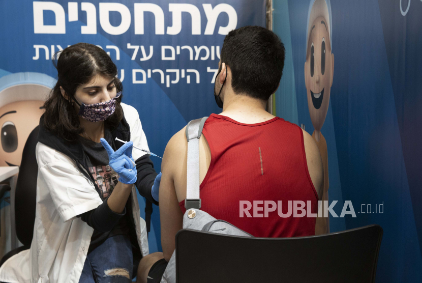 Seorang pria Israel menerima suntikan vaksin virus corona dari seorang profesional medis dengan Layanan Kesehatan Clalit di kompleks Cinema City di Yerusalem, Senin, 30 Agustus 2021. Israel telah menyetujui dosis vaksin keempat untuk kelompok paling rentan Covid-19.
