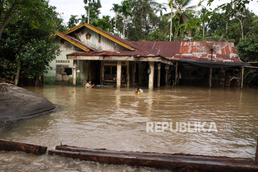 Warga bermain dengan banjir di depan rumahnya di Aceh.