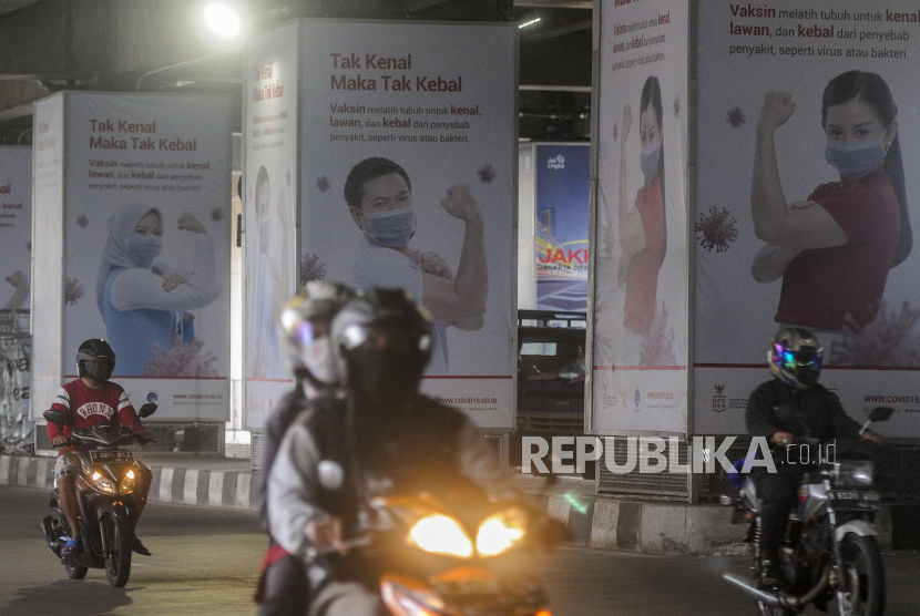 Kendaraan melintas di dekat baliho sosialisasi manfaat vaksinasi Covid-19 di kawasan Lebak Bulus, Jakarta. Presiden Joko Widodo, Rabu (16/12), mengumumkan vaksin Covid-19 akan diberikan gratis kepada masyarakat.