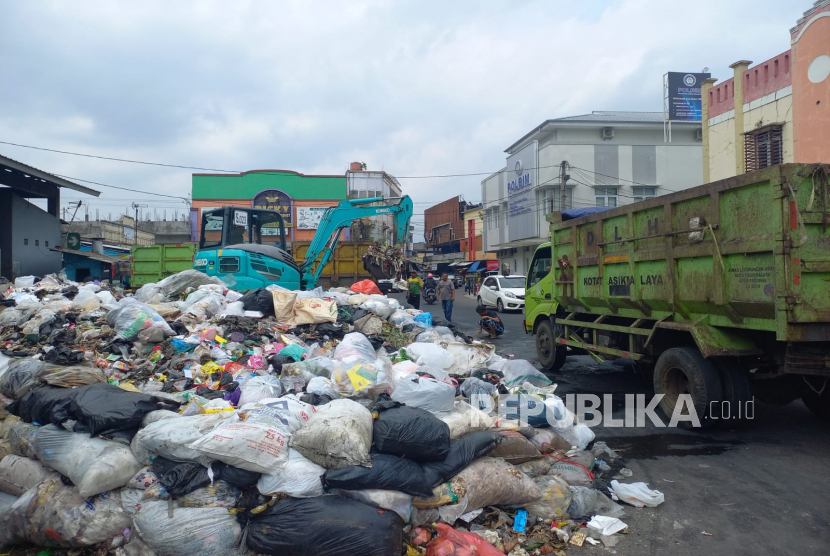 Warga melintas di depan TPS Pasar Kidul, Kecamatan Cihideung, Kota Tasikmalaya, Jumat (27/1/2023). Sampah di TPS itu mengalami penumpukan hingga hampir meluap ke jalan. 