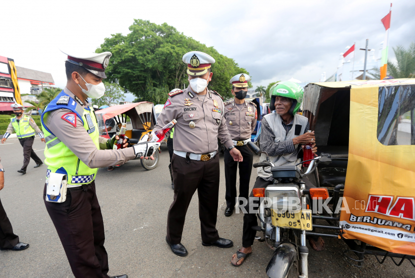 Dirlantas Polda Aceh Kombes Pol Dicky Sondani (tengah) bersama personel membagikan sirup dan takjil untuk berbuka puasa kepada pengendara becak motor di depan Masjid Raya Baiturrahman, Kota Banda Aceh, Provinsi Aceh, Jumat (8/4/2022). 