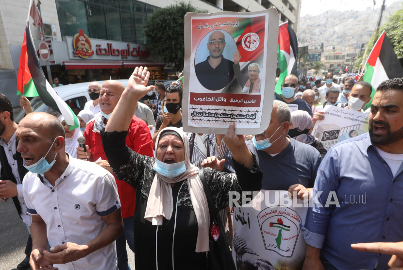  Wanita Palestina memegang poster dengan foto tahanan Palestina yang ditahan di penjara Israel selama protes terhadap perjanjian perdamaian untuk menjalin hubungan diplomatik antara Israel dan Uni Emirat Arab, di kota Nablus, Tepi Barat, 15 September 2020. 