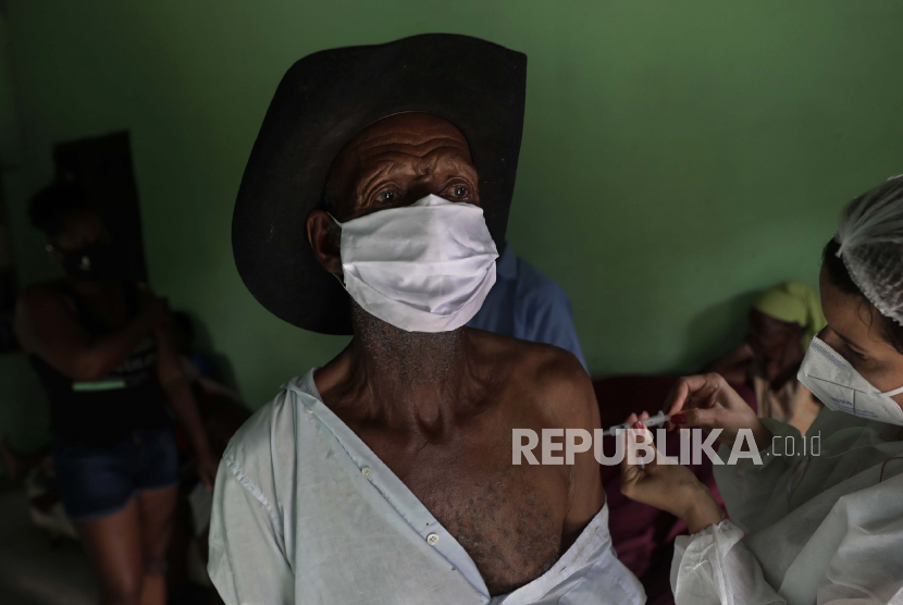  Mengenakan masker untuk mengekang penyebaran virus korona baru, Algemiro Dias yang berusia 82 tahun mendapatkan suntikan vaksin Sinovac pertamanya, di komunitas Kalunga Vao de Almas, daerah pedesaan di pinggiran Cavalcante, negara bagian Goias, Brasil, Senin, 15 Maret 2021.