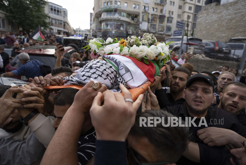 Pelayat Palestina membawa jenazah Shireen Abu Akleh keluar dari kantor Al Jazeera setelah teman dan kolega memberikan penghormatan, di kota Ramallah, Tepi Barat, Rabu, 11 Mei 2022. 