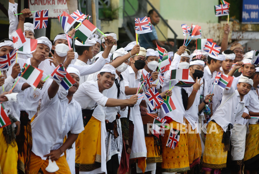 Pelajar Bali mengibarkan bendera negara anggota G20 saat kedatangan para pemimpin G20, di sepanjang jalan dekat bandara Internasional Ngurah Rai di Bali, Indonesia, 14 November 2022. KTT Kepala Negara dan Pemerintahan Kelompok Dua Puluh (G20) ke-17 akan diadakan di Bali mulai 15 hingga 16 November 2022.