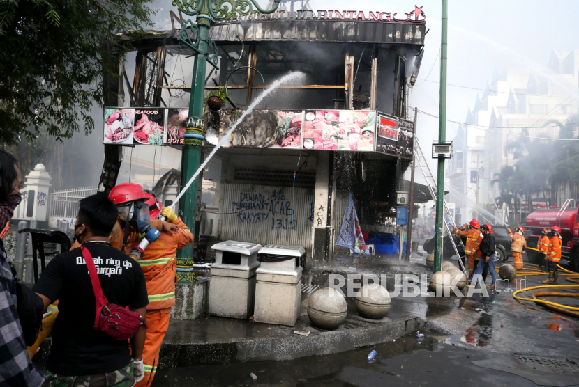 Petugas memadamkan api ruko yang terbakar saat unjuk rasa tolak Omnibus Law  di Malioboro, Yogyakarta, Kamis (8/10).