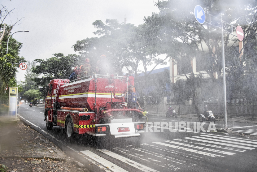 Petugas dari Dinas Pemadam Kebakaran dan Penanggulangan Bencana (Diskar PB) Kota Bandung menyemprotkan cairan disinfektan di ruas Jalan Kota Bandung