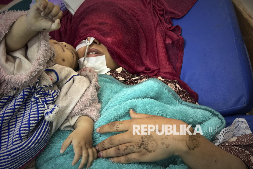 Shaima Seiam, 23, terbaring terluka di Rumah Sakit Nasser di samping jenazah bayi perempuannya, Ahlam, setelah rumah mereka terkena serangan udara Israel di Khan Younis, Jalur Gaza, Rabu, 16 April 2025.