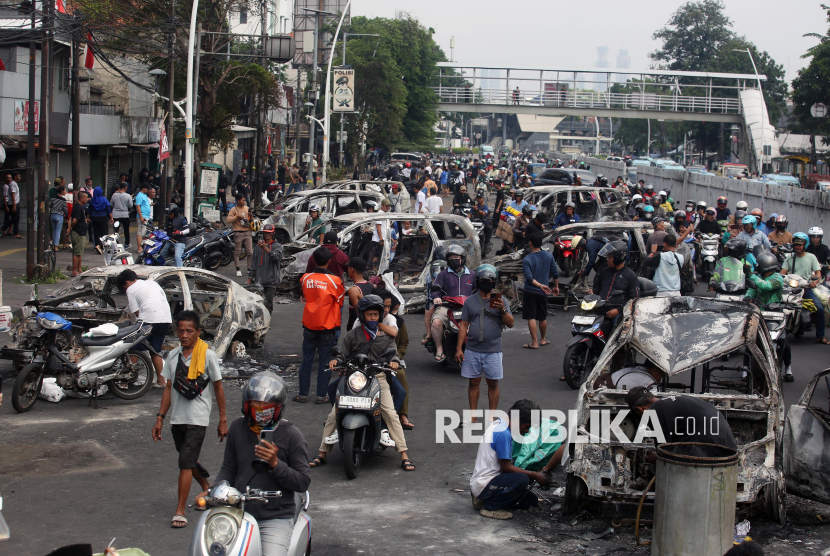 Warga mengamati sejumlah mobil yang hangus terbakar di Jalan Matraman, Jakarta Timur, Sabtu (30/8/2025). Sebanyak 12 mobil yang terparkir di Jalan Matraman terbakar saat berlangsung aksi unjuk rasa yang berakhir ricuh. 