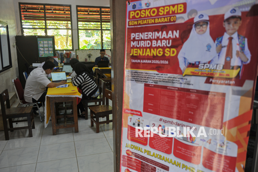 Tenaga pendidik membantu orang tua murid saat proses pendaftaran Sistem Penerimaan Murid Baru (SPMB) 2025 di SDN Pejaten Barat 01.