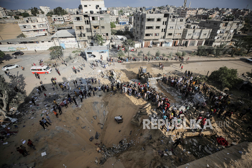 Warga Palestina mencari mayat dan korban selamat di puing-puing bangunan tempat tinggal yang rata akibat serangan udara Israel, di kamp pengungsi Khan Younis di Jalur Gaza selatan, 16 Oktober 2023.