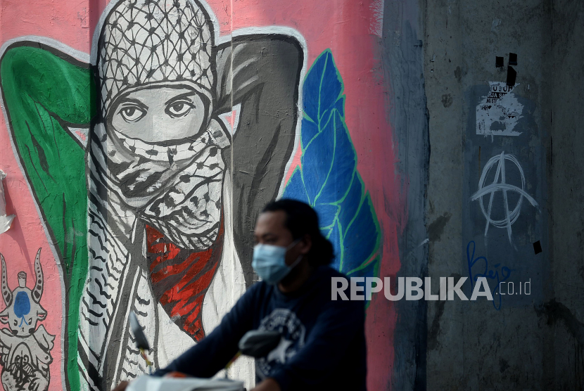 Pengendara melintas di dekat mural bertema dukungan kepada Palestina yang menjadi korban kebiadaban Zionis Israel di Jalan Ciledug Raya, Jakarta Selatan, Selasa (25/5). 