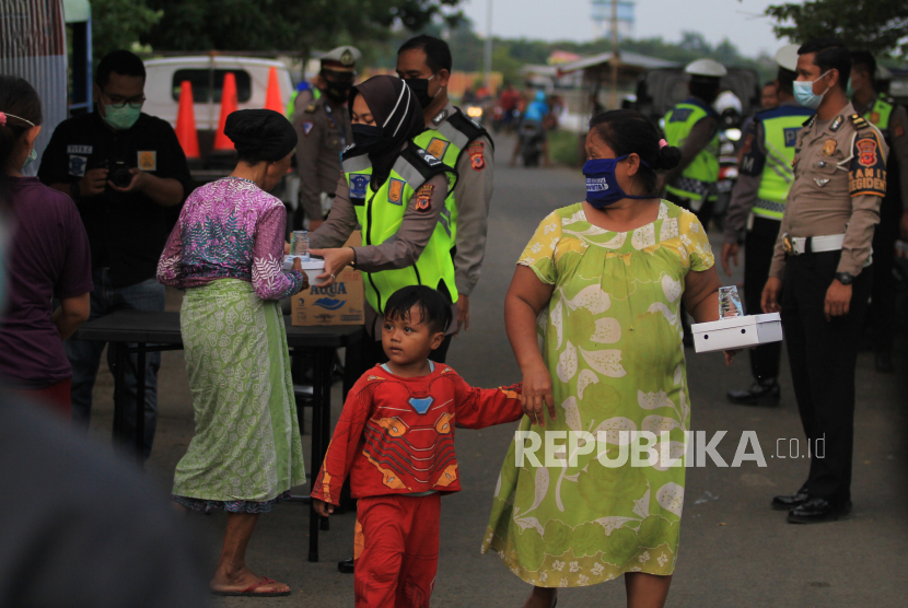 Polisi membagikan makanan untuk berbuka puasa kepada warga di kelurahan Bojongsari, Indramayu, Jawa Barat, Rabu (6/5/2020). Pembagian paket makanan berbuka puasa dari dapur umum Polres Indramayu itu sebagai bentuk kepedulian dan meringankan beban masyakarat di tengah pandemi COVID-19