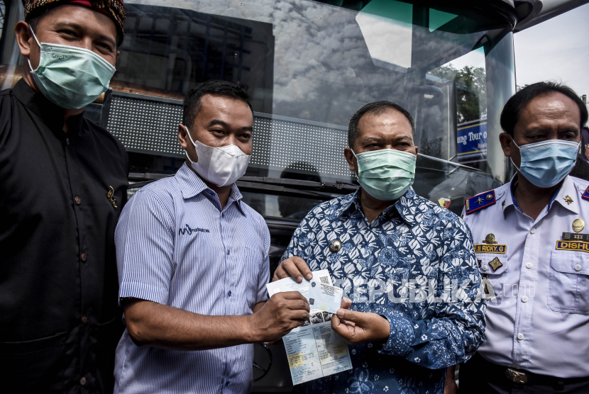 Wali Kota Bandung Oded M Danial (kedua kanan) menyerahkan Elektronik Sertifikat Registrasi Uji Tipe (e-SRUT) dan Bukti Lulus Uji Elektronik (BLUe) kepada warga usai diluncurkan di Balai Pengujian Kendaraan Bermotor Dishub Kota Bandung, Jalan Sor GBLA, Gedebage, Kota Bandung, Kamis (5/11). Pemerintah Kota Bandung melalui Dishub Kota Bandung bekerja sama dengan Bank BJB meluncurkan metode pembayaran non-tunai menggunakan QRIS untuk pembayaran Pengujian Kendaraan Bermotor (PKB), tiket bus Bandros, Trans Metro Bandung dan pelayanan sistem derek guna meningkatkan pelayanan sekaligus memudahkan warga untuk transaksi tanpa kontak fisik. Foto: Abdan Syakura/Republika