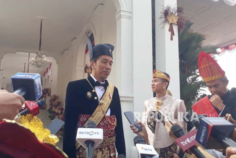 Presiden Jokowi mengenakan pakaian adat Ageman Songkok Singkepan Ageng. Ketua DPP sebut jika Ganjar pasang foto Jokowi wajar tapi kalau capres lain tak etis.