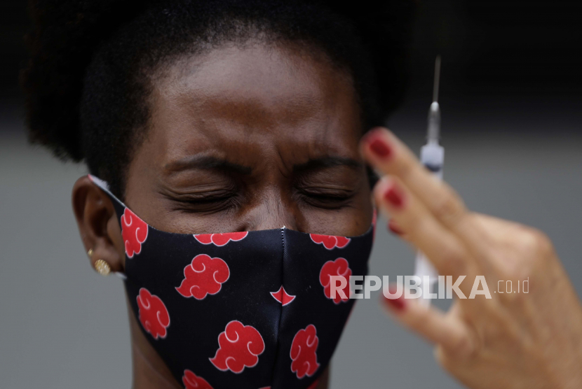 Seorang wanita bereaksi saat melihat jarum suntik vaksin Sinovac untuk COVID-19 saat petugas kesehatan memvaksinasi penduduk di quilombo Kalunga Vao de Almas di pinggiran Cavalcante, negara bagian Goias, Brasil, Selasa, 16 Maret 2021.
