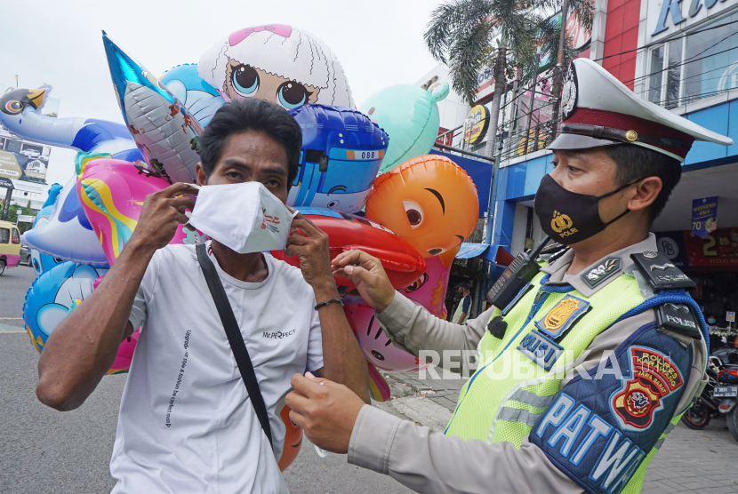 Anggota Satlantas Polres Karawang membantu memakaikan masker kepada warga pengguna jalan saat Operasi Keselamatan Lodaya 2022 di Karawang, Jawa Barat, Selasa (1/3/2022). Operasi Lodaya tersebut ditujukan untuk menurunkan Lakalantas, pelanggaran lalu lintas serta penerapan protokol kesehatan agar masyarakat tertib dalam berlalu lintas di masa pandemi COVID-19. 