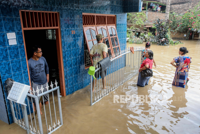  Orang-orang berdiri di luar rumah mereka di daerah pemukiman yang terendam banjir di Medan, Sumatera Utara, Indonesia, 05 Desember 2020.