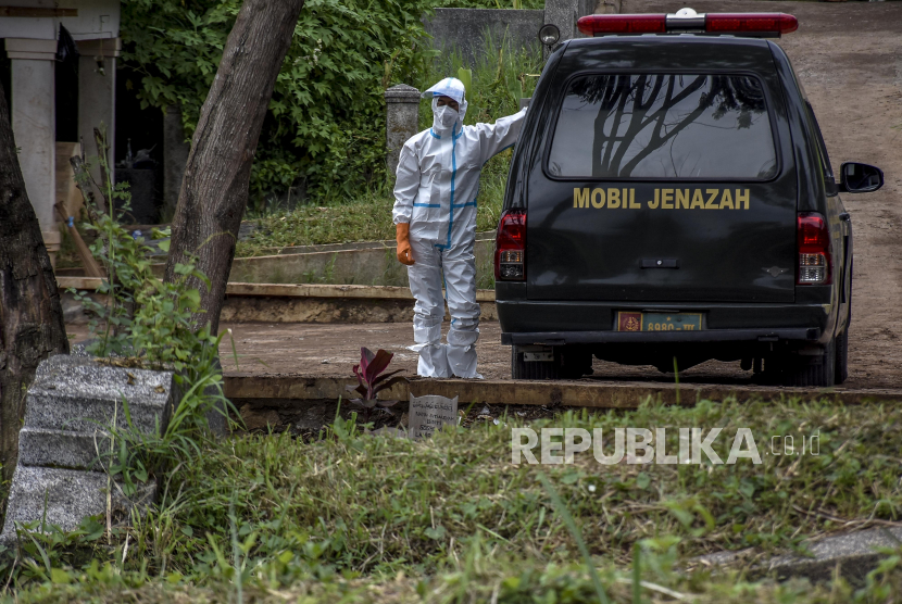 Petugas rumah sakit berdiri di dekat ambulans yang membawa jenazah dengan protokol Covid-19 di TPU Cikadut, Jalan Cikadut, Mandalajati, Kota Bandung, Jumat (29/1). Ilustrasi