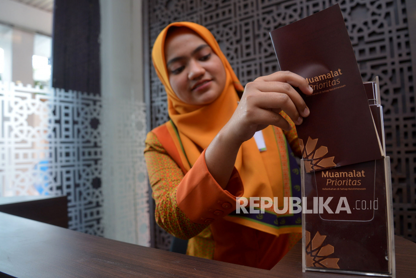 Karyawan PT Bank Muamalat Indonesia Tbk menata brosur produk dalam peresmian pembukaan layanan Priority Center di kantor Cabang Buaran, Jakarta, Kamis, (8/12). Otoritas Jasa Keuangan (OJK) memastikan akan menyusun regulasi untuk menambah fungsi baru dari bank syariah. 