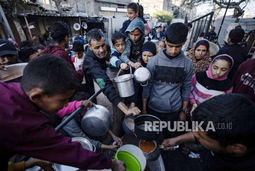 Pengungsi Palestina berkumpul untuk mengumpulkan makanan yang disumbangkan oleh kelompok pemuda amal sebelum sarapan, pada hari kedua bulan suci Ramadhan di Rafah, di selatan Jalur Gaza, (12/3/ 2024).