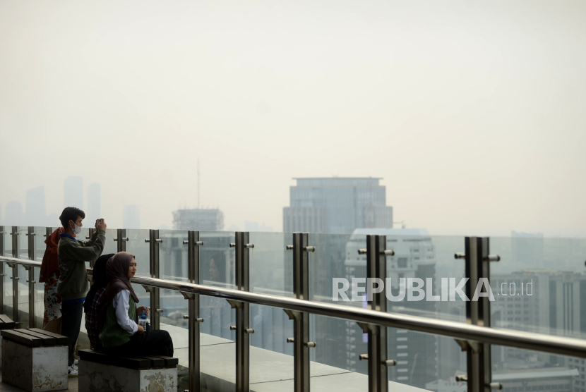 Warga melihat suasana gedung-gedung bertingkat yang tertutup oleh kabut polusi di Jakarta, Selasa (25/7/2023).