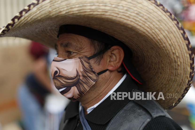 Seorang pria yang mengenakan masker pelindung saat melintasi kios-kios yang telah dibuka kembali di Mexico, Kamis (25/ 6). Amerika Latin sekarang menjadi pusat pandemi, tetapi dengan ratusan juta orang bergantung pada pasar-pasar ini untuk makanan dan mata pencaharian, apakah dan bagaimana mereka bisa beroperasi dengan aman.(AP Photo/Rebecca Blackwell)