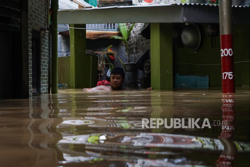 Seorang warga menerobos banjir yang merendam rumah di kawasan Kebon Pala, Kampung Melayu, Jakarta. Pj Gubernur DKI Jakarta Heru Budi diskusi penanganan banjir dengan Walkot Melbourne.