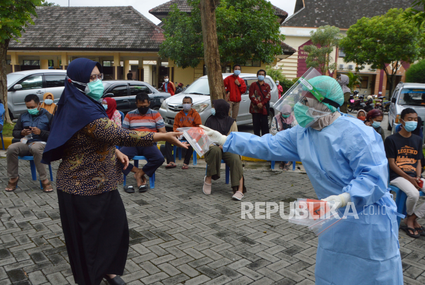Petugas kesehatan membagikan alat tes usap kepada warga sebelum tes usap massal di halaman Wisma Haji Kota Madiun, Jawa Timur, Selasa (19/1/2021). Pemkot Madiun memfasilitasi tes usap secara gratis bagi warga yang memiliki riwayat kontak erat dengan pasien positif COVID-19 guna pencegahan penyebaran SARS-CoV-2 seiring dengan terus meningkatnya jumlah kasus positif COVID-19 hingga daerah tersebut berstatus zona merah. 